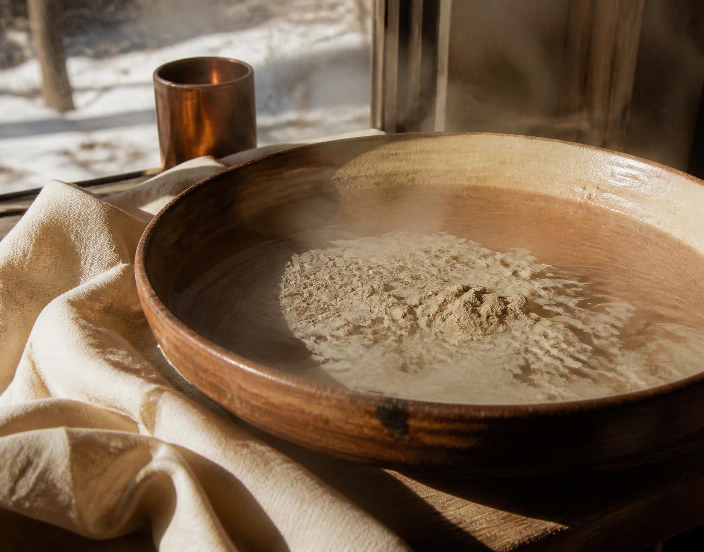 Clay blooming in warm water beside linen in late winter light